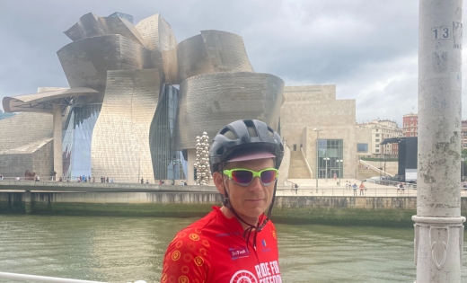 Dr J Simon Rofe in cycling gear standing outside the Guggenheim Bilbao Museum