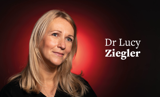 Dr Lucy Ziegler, in black, in front of a red colour splash