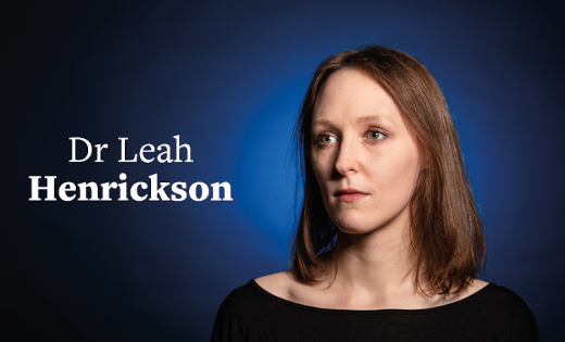 Dr Leah Henrickson in front of a black background with a blue colour splash.