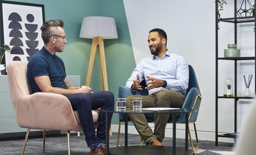 Two men having a chat inside a room sat on chairs