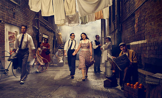 Promotional image of Street Scene at Opera North. Two characters walking down a set.