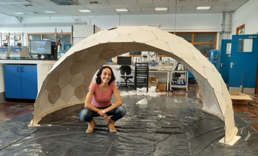 Ornella Iurio crouches under an arch in a laboratory