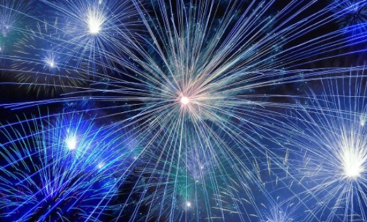 A number of blue and white fireworks going off against a night sky.