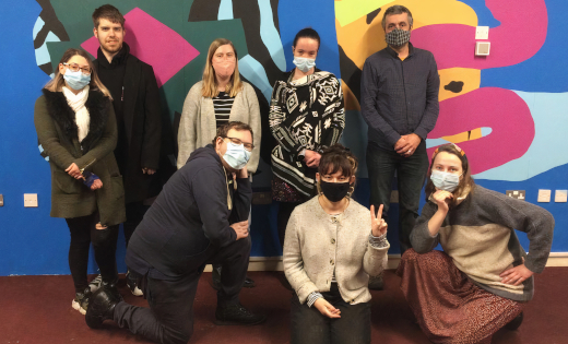 The Irregular Art Schools team pose in masks at an exhibition.