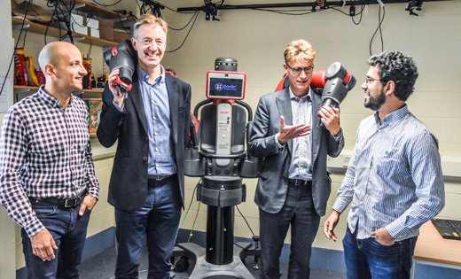 Computing PhD researcher, Wissam Bejjani (far left), and post-doctoral researcher, Luis Figuerdo (far right), explain to Jon Andrews and Ian Morrison from PwC how Baxter the robot is used in their research. October 2018