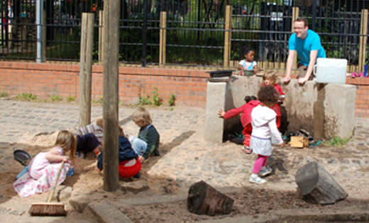 Photograph of children and staff from Bright Beginnings playing outdoors with sand.