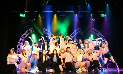 Image from K-pop dance society performance showing students on stage smiling.