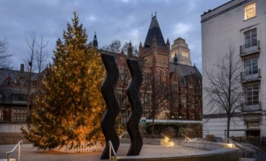 An image of the Christmas tree on campus, lit up behind the 'Sign for Art' sculpture. The Great Hall and Parkinson Building are in the background.