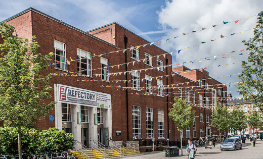 A shot of the outside of the Refectory building, with bunting up over the plaza. October 2020.