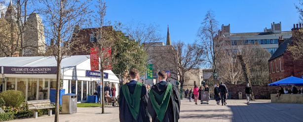 Two graduates outside the Student's Union on a sunny day.