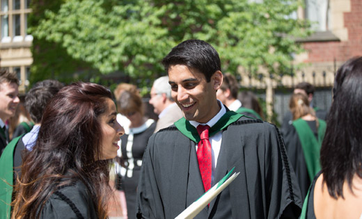 Two smiling students outside their graduation ceremony.